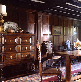 Inside the house a table and chair sit in the wood paneled entrance hall